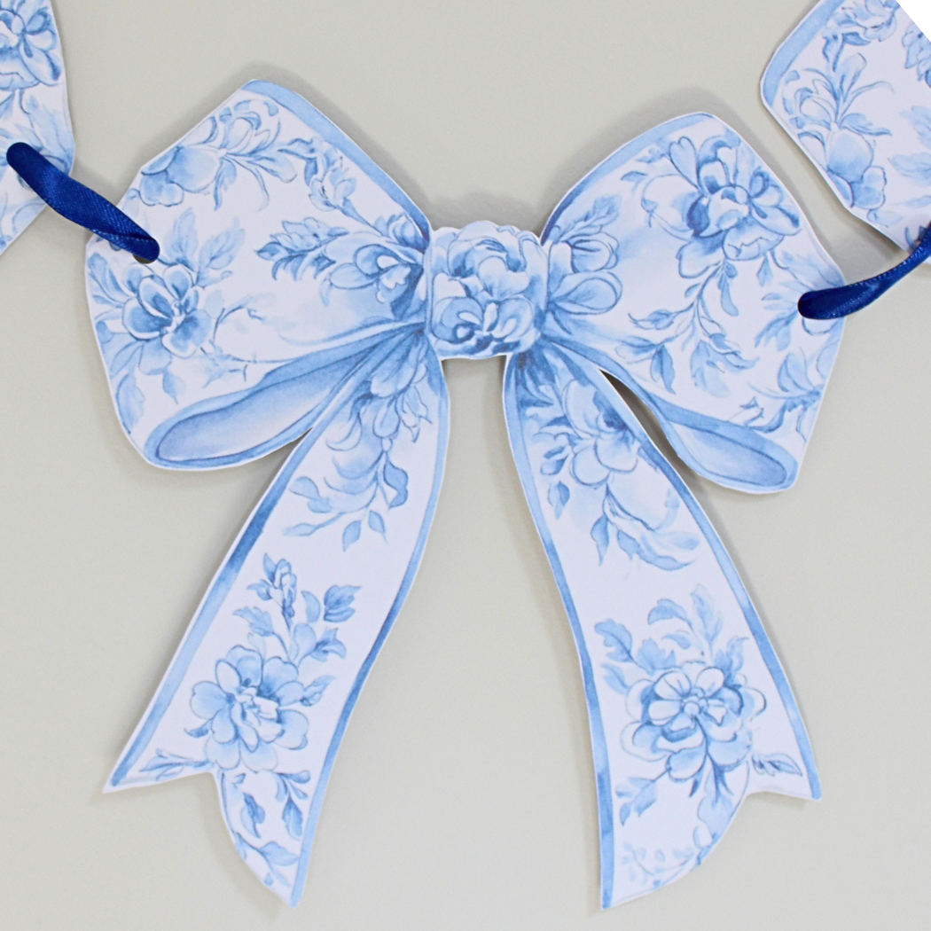 A blue and white floral patterned bow garland made of cardstock, tied with a ribbon.