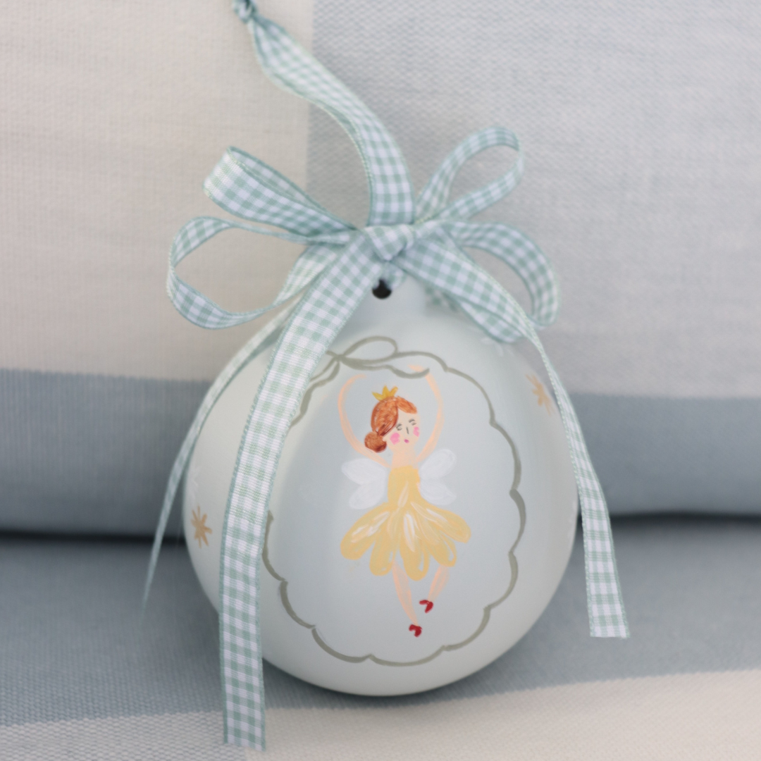 Decorative christmas bauble with a ballerina design and a blue ribbon on a neutral background