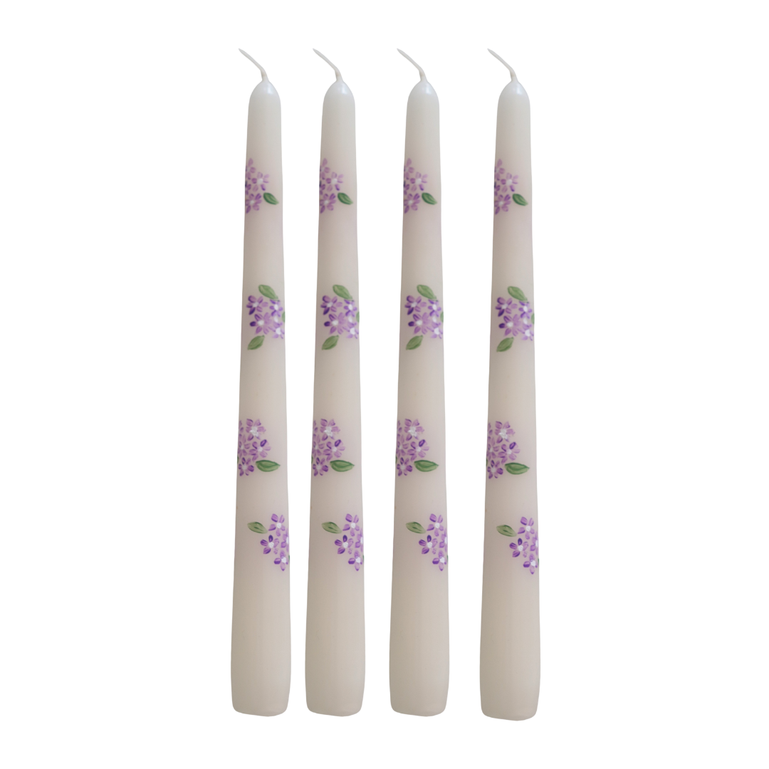 Four white candles with purple floral patterns on a white background