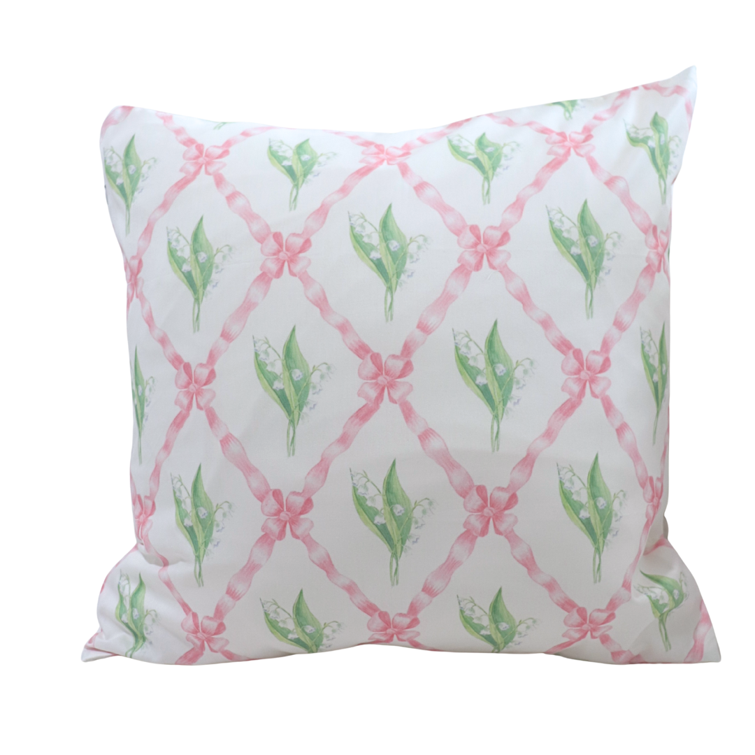 Decorative pillow with pink ribbons and green leaves on a white background