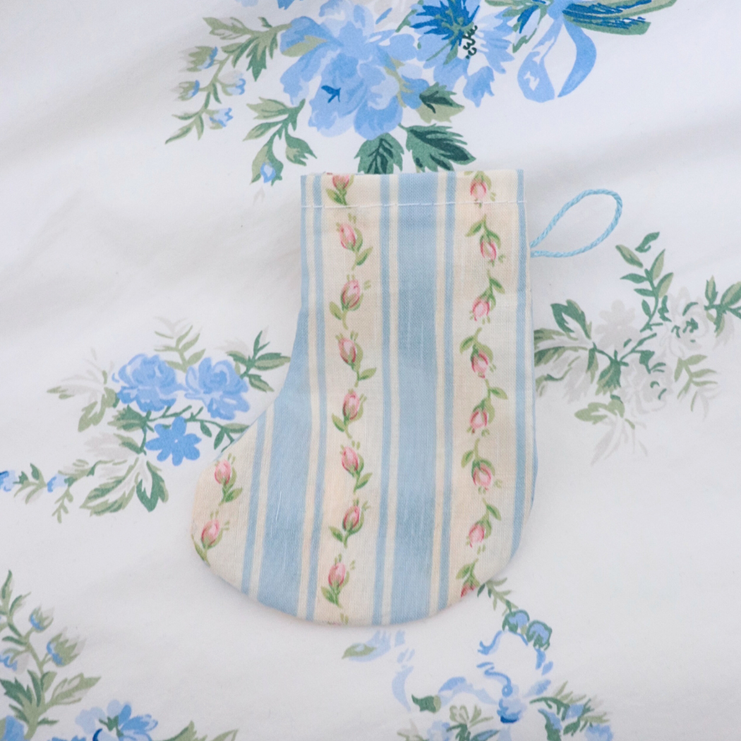 Fabric swatch with blue and pink striped pattern on a floral background