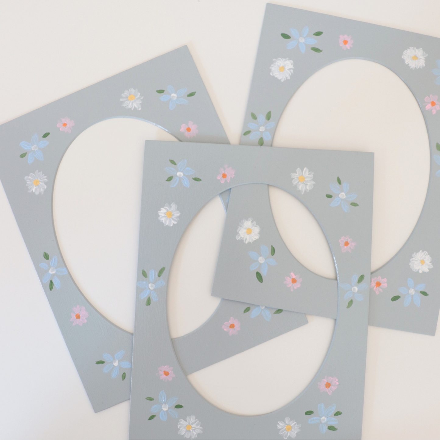 Three gray oval-shaped coasters with floral patterns on a white background