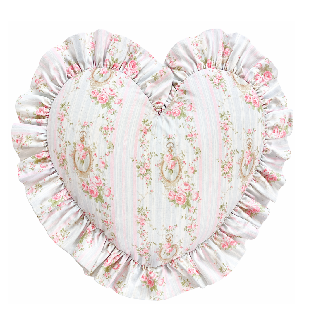 Heart-shaped pillow with floral pattern and ruffled edge on a white background