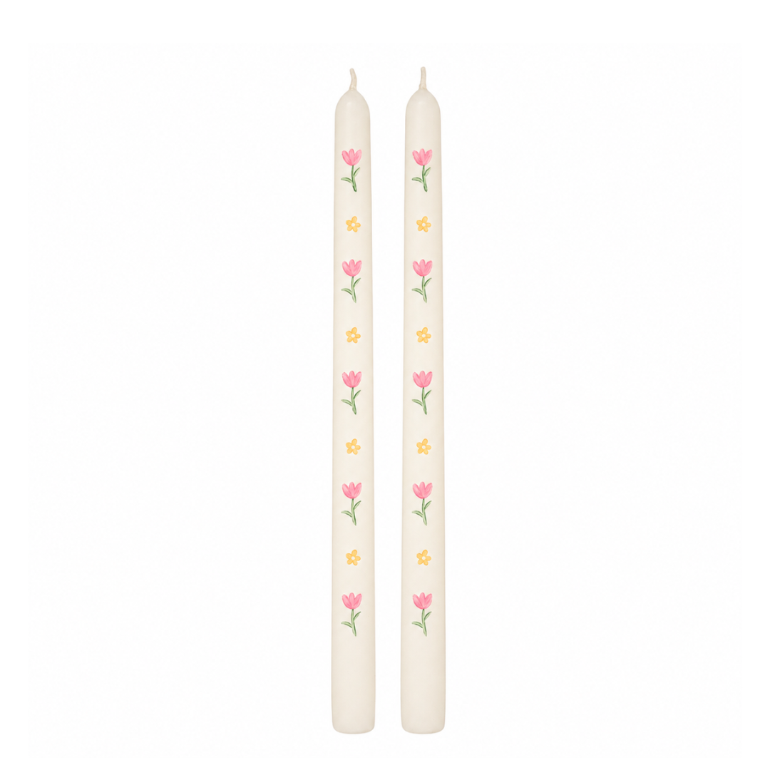 Two white candles with floral designs on a white background