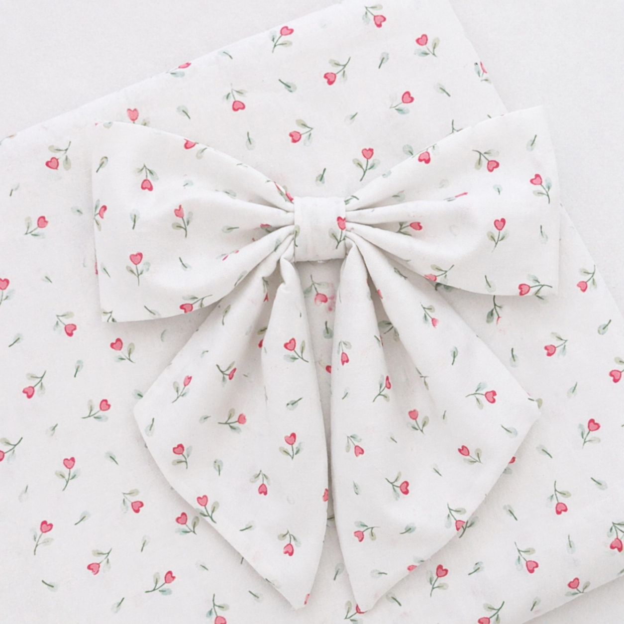 White fabric with small pink floral pattern and a knot in the center.
