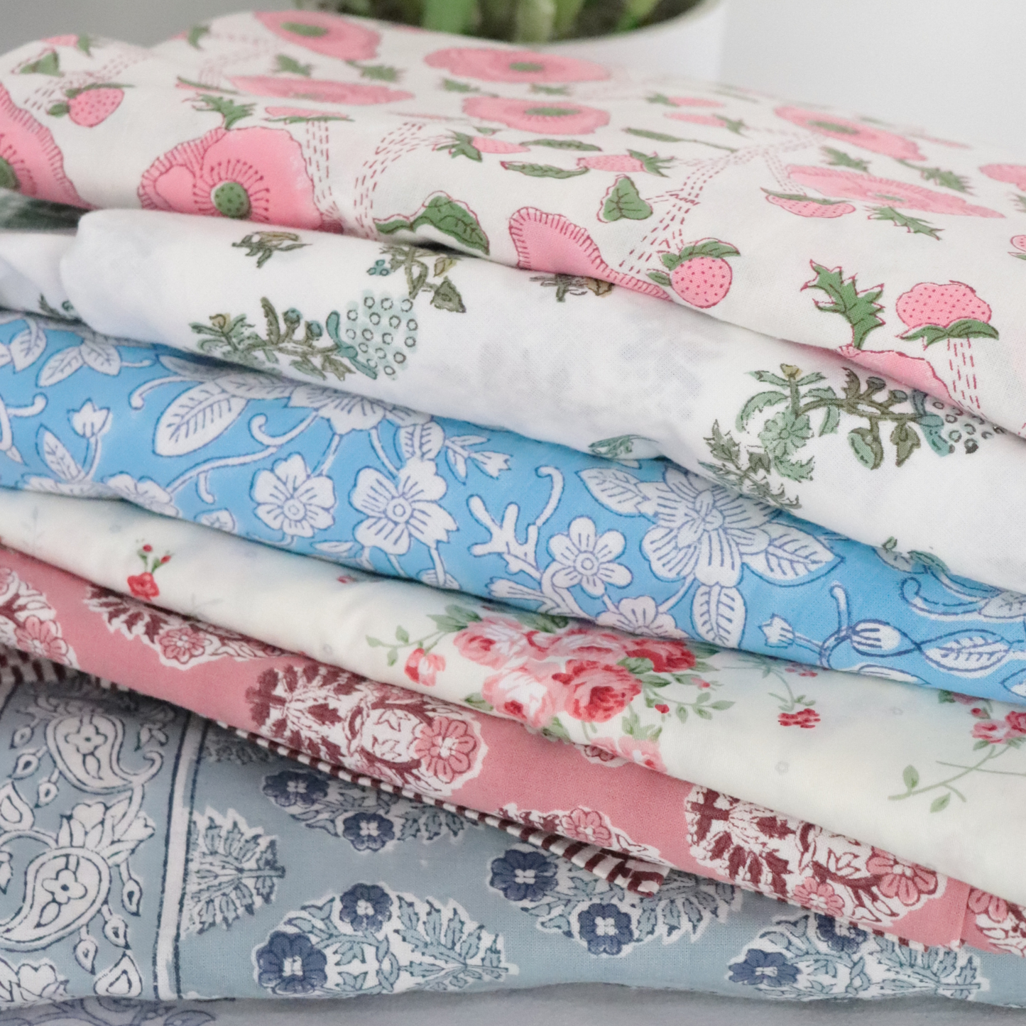 Stack of folded fabric with floral patterns on a neutral background