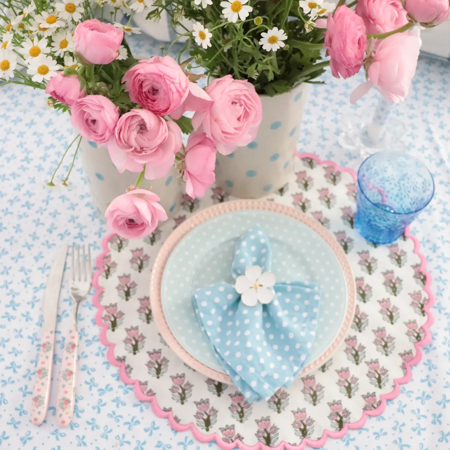 Decorative table setting with pink flowers, a heart-shaped plate, and floral placemat.