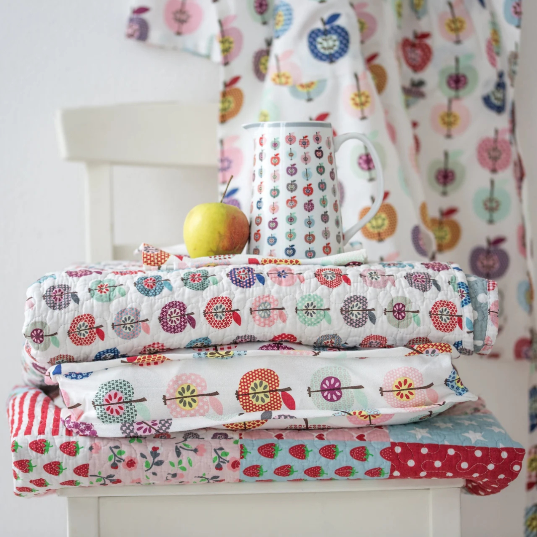 Stack of colorful patterned blankets on a white chair with a white background