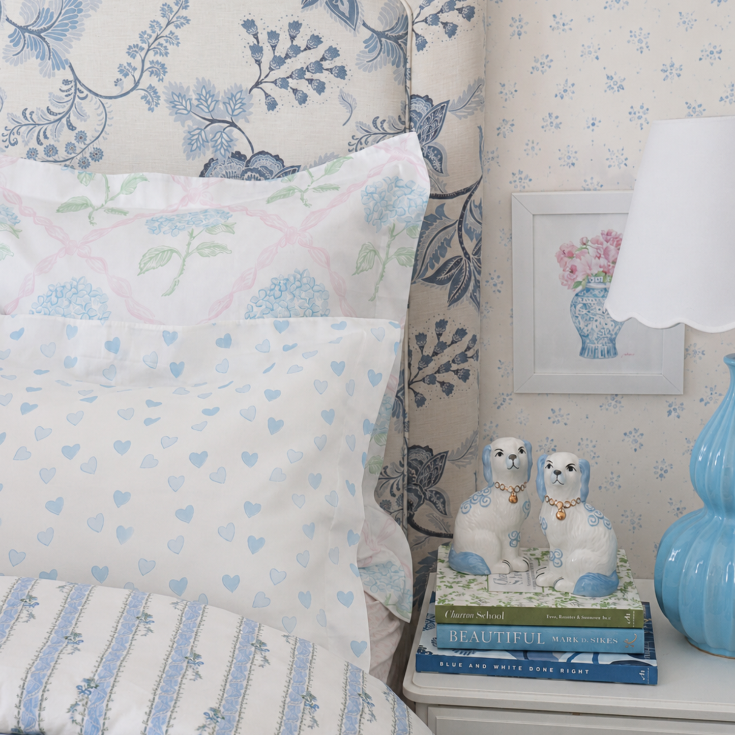 Floral and heart-patterned pillows on a bed with decorative items on a nightstand.