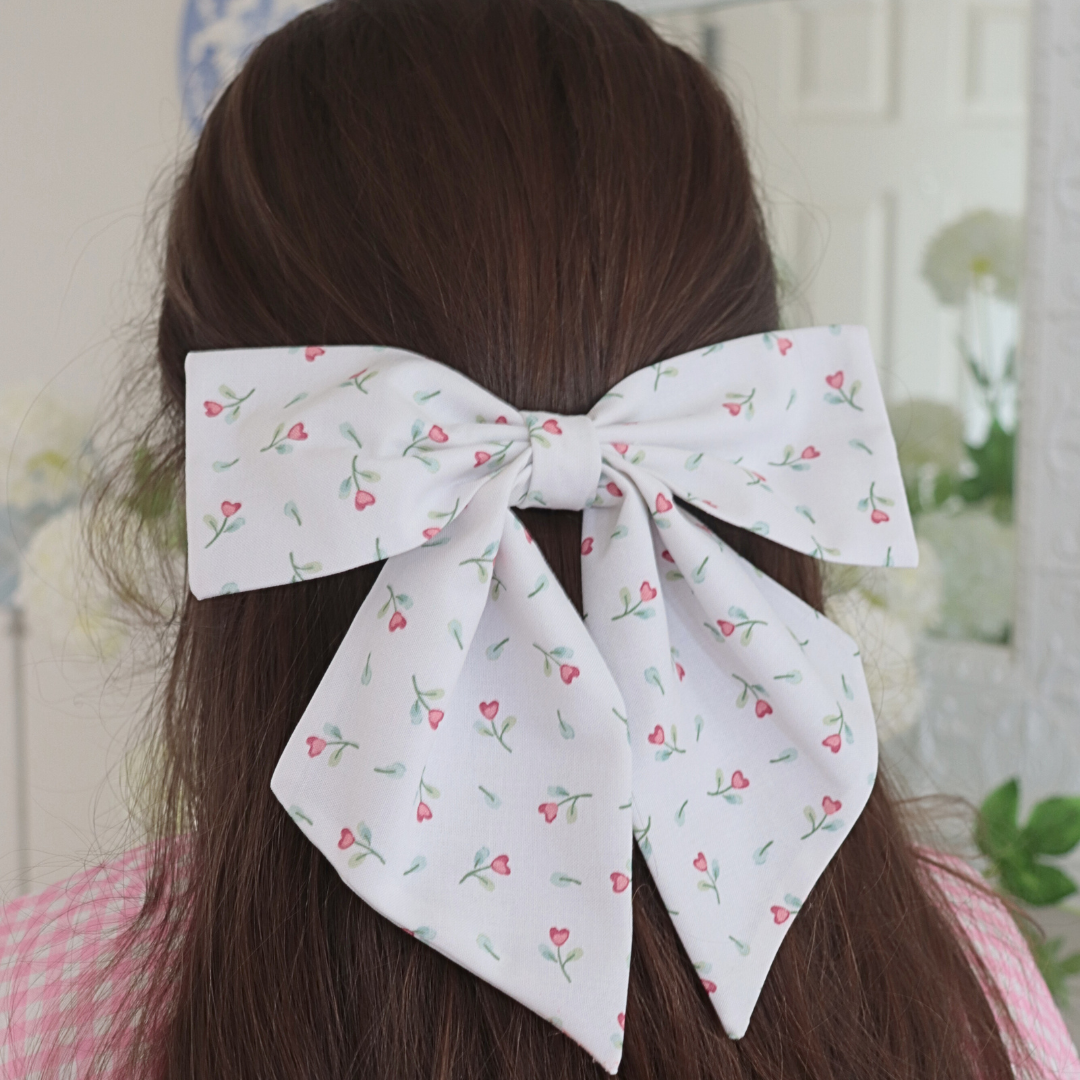 White floral bow in a person's hair with a blurred background